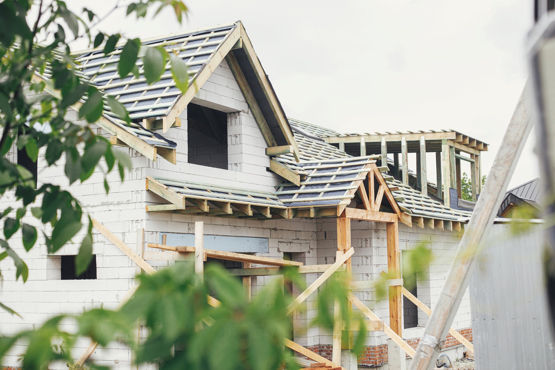 Unfinished modern farmhouse building. Wooden roof framing of